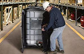 Technician installing a DEF tote heater on a 330-gallon tank for maintaining fluid temperature.