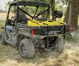 UTV sprayer setup with a yellow tank and hose reel, spraying a field for agricultural purposes.
