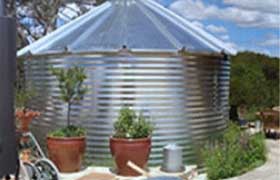 Small corrugated tank with a roof installed in a backyard