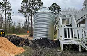 Corrugated steel tank being installed next to a home