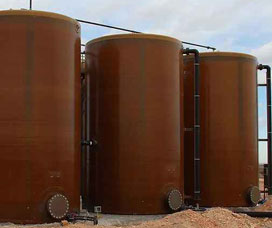 Three fiberglass tanks side by side on a concrete pad