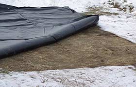Ground thawing blanket laid on frozen ground to prepare the surface for excavation or construction.
