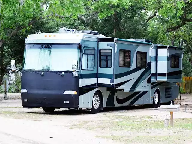 A large blue and white recreational vehicle (RV) parked among trees, ideal for camping or road trips.