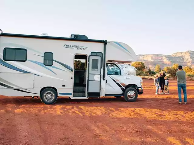 a man taking a photo of his family next to a RV