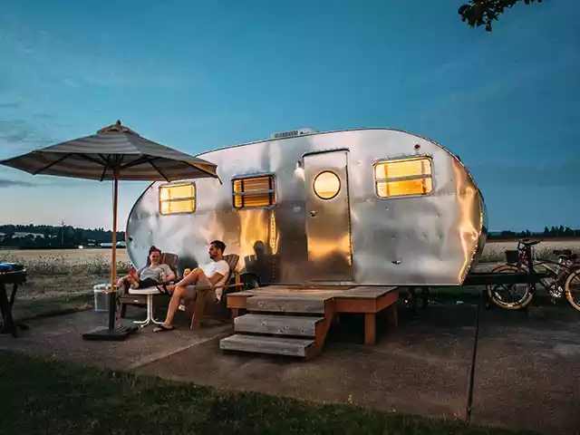 a couple sitting in front of a camper